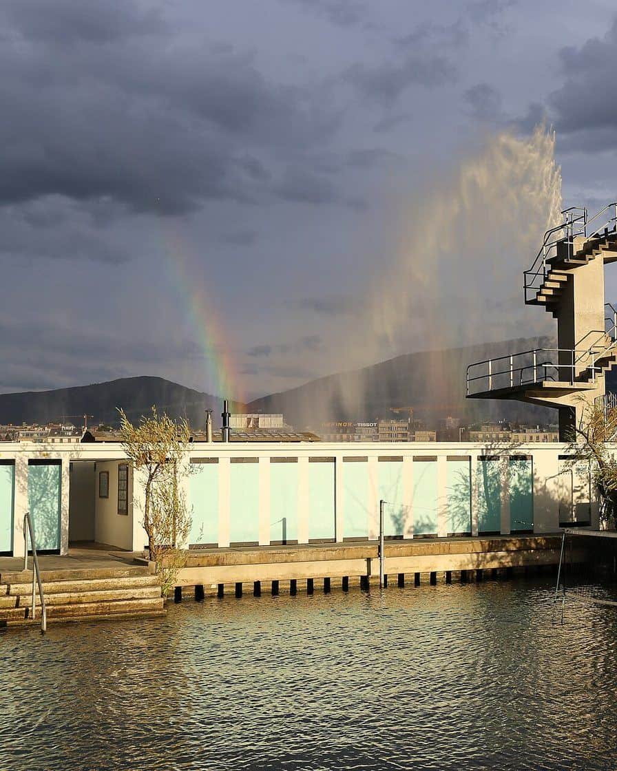La jetée des Bains des Pâquis à Genève, avec ses cabines, ses pontons et des baigneurs au bord du lac Léman