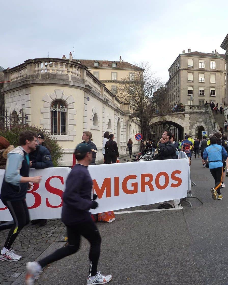 Coureurs de la Course de l'Escalade dans les rues pavées de la Vieille Ville de Genève en décembre, encouragés par le public