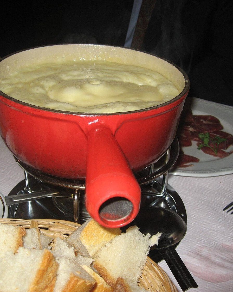 Caquelon de fondue au fromage sur une table en bois au bord du lac Léman à Genève, un soir d'hiver