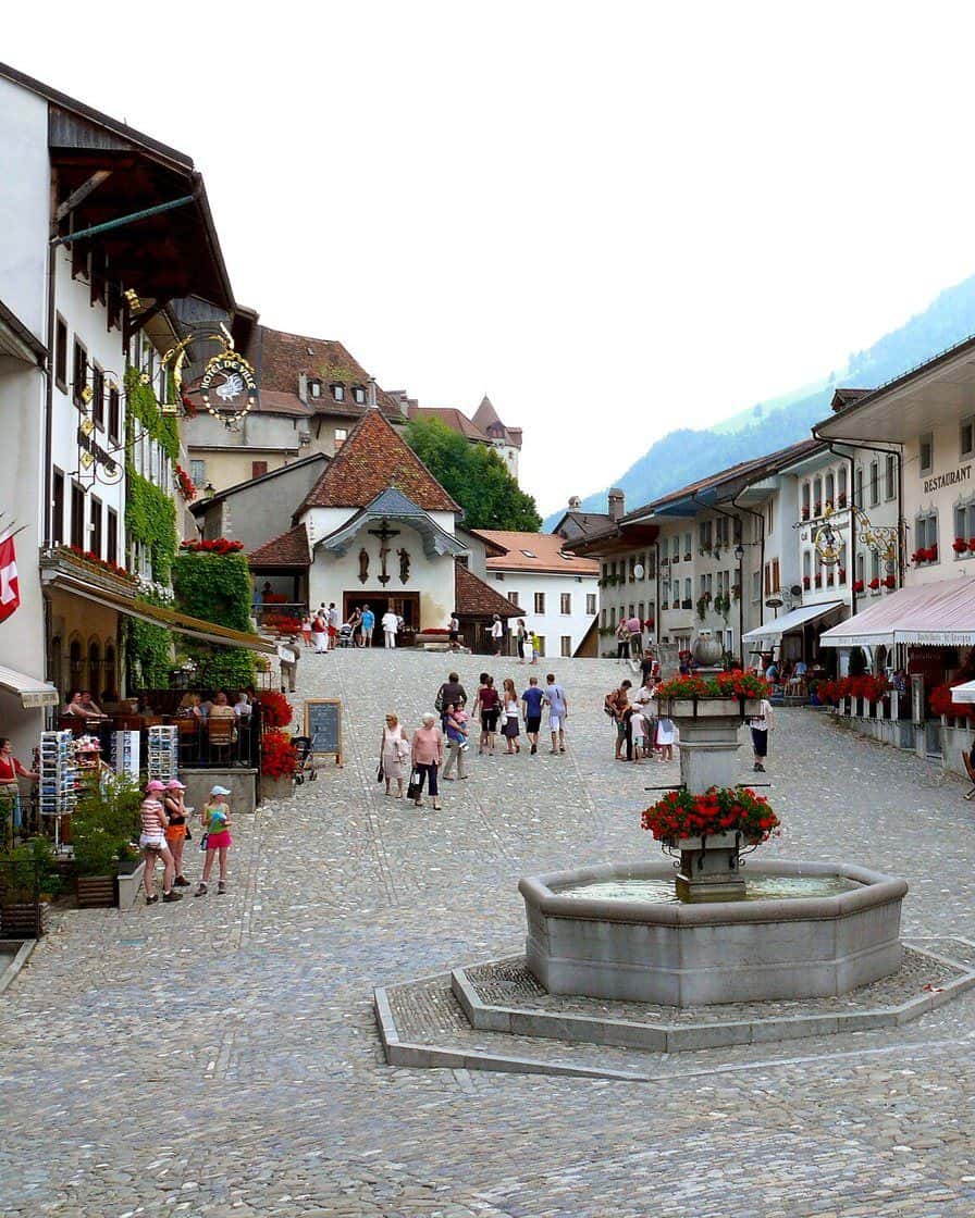 La via principale lastricata del borgo medievale di Gruyères e il suo castello sulla collina, nelle Prealpi friburghesi