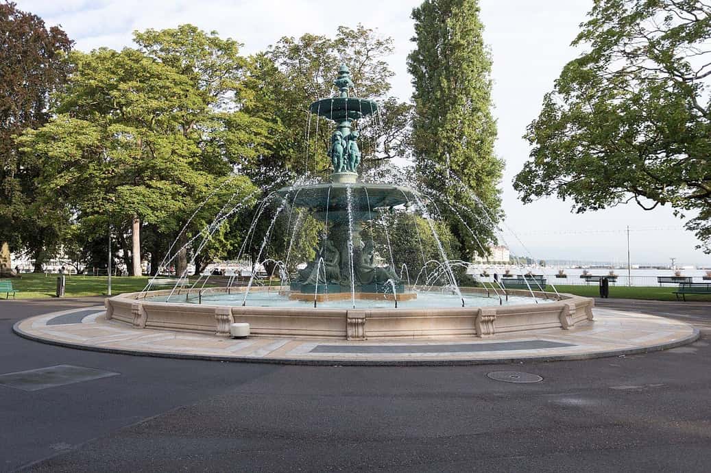 La gran fuente del Jardin Anglais de Ginebra, rodeada de árboles, junto al lago
