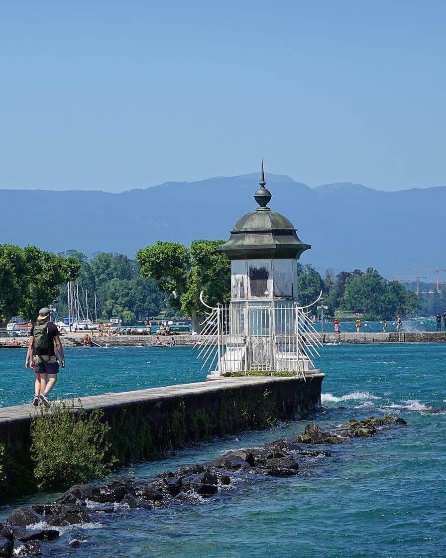 The Eaux-Vives pier in Geneva with people walking at the foot of the Jet d'eau and spray carried by the wind