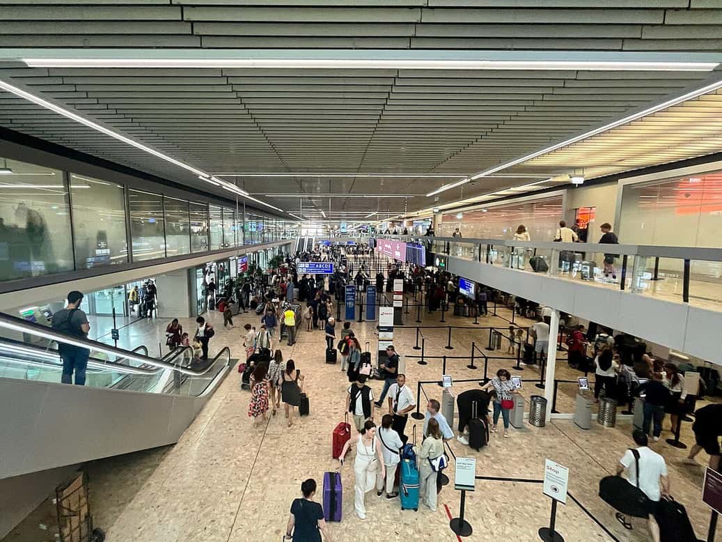 El vestíbulo del aeropuerto de Ginebra, con viajeros y sus maletas bajo la gran cristalera